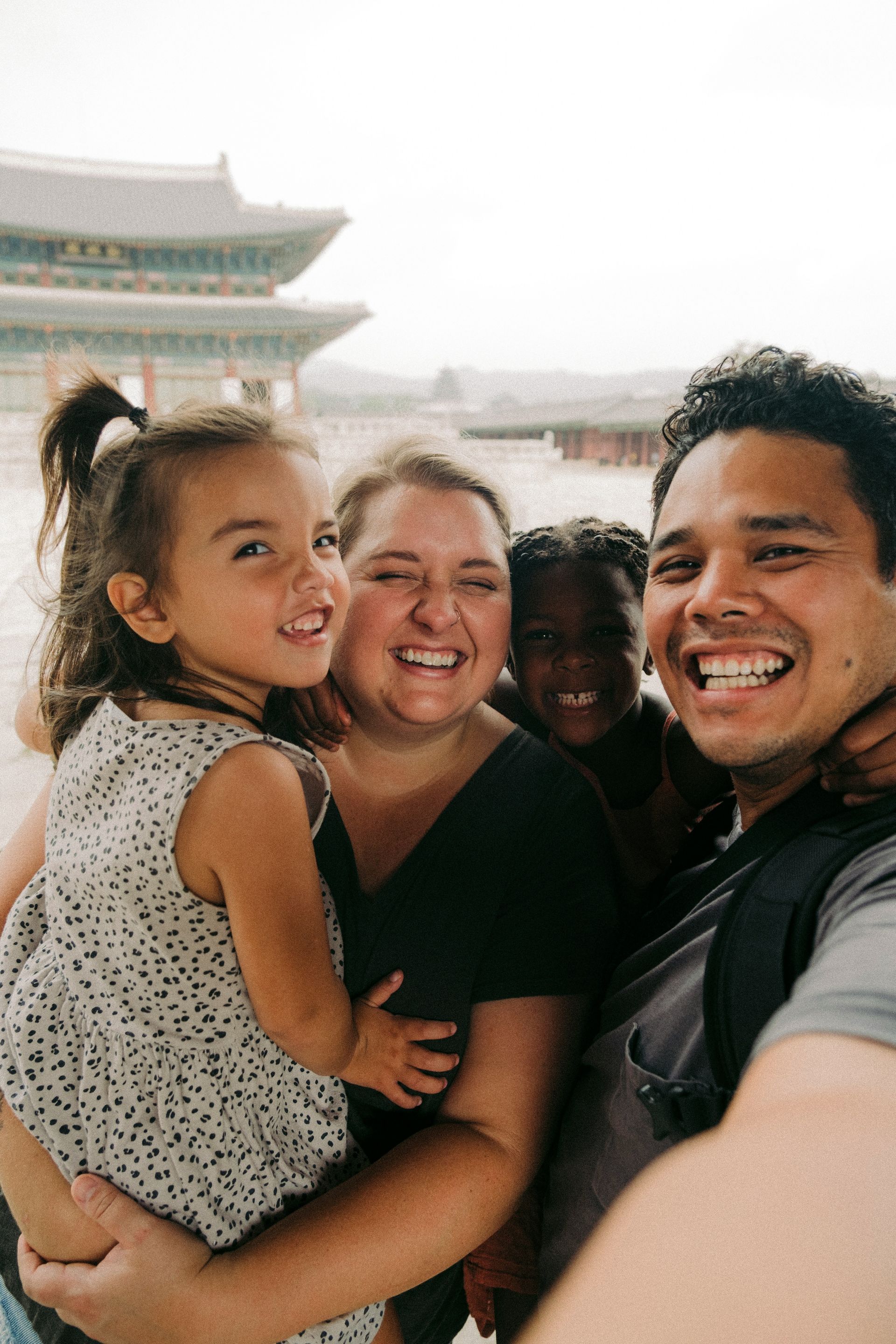 Smiling family taking a selfie in front of a traditional temple building