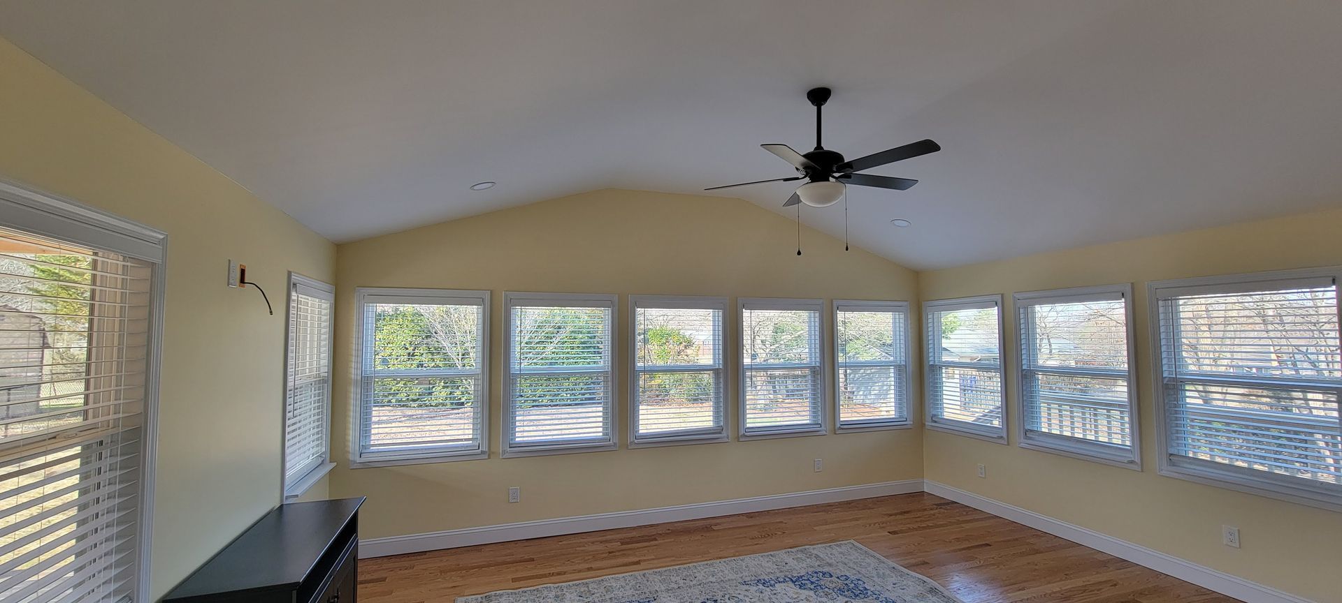 A living room with a lot of windows and a ceiling fan.