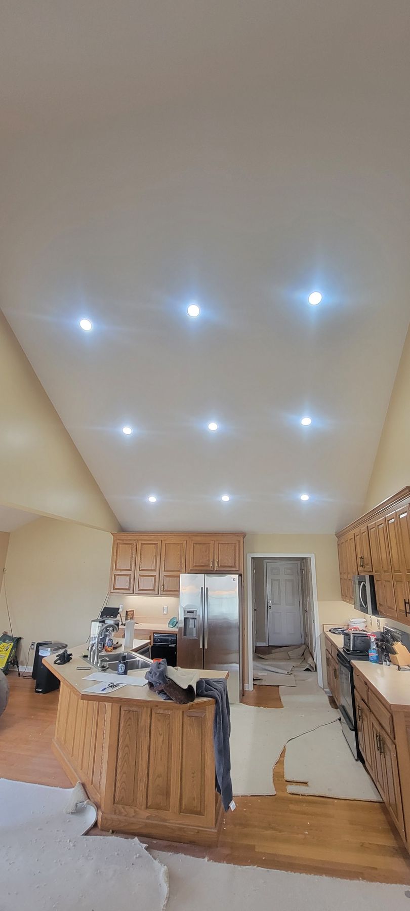 A kitchen with a white ceiling and wooden cabinets is being remodeled.