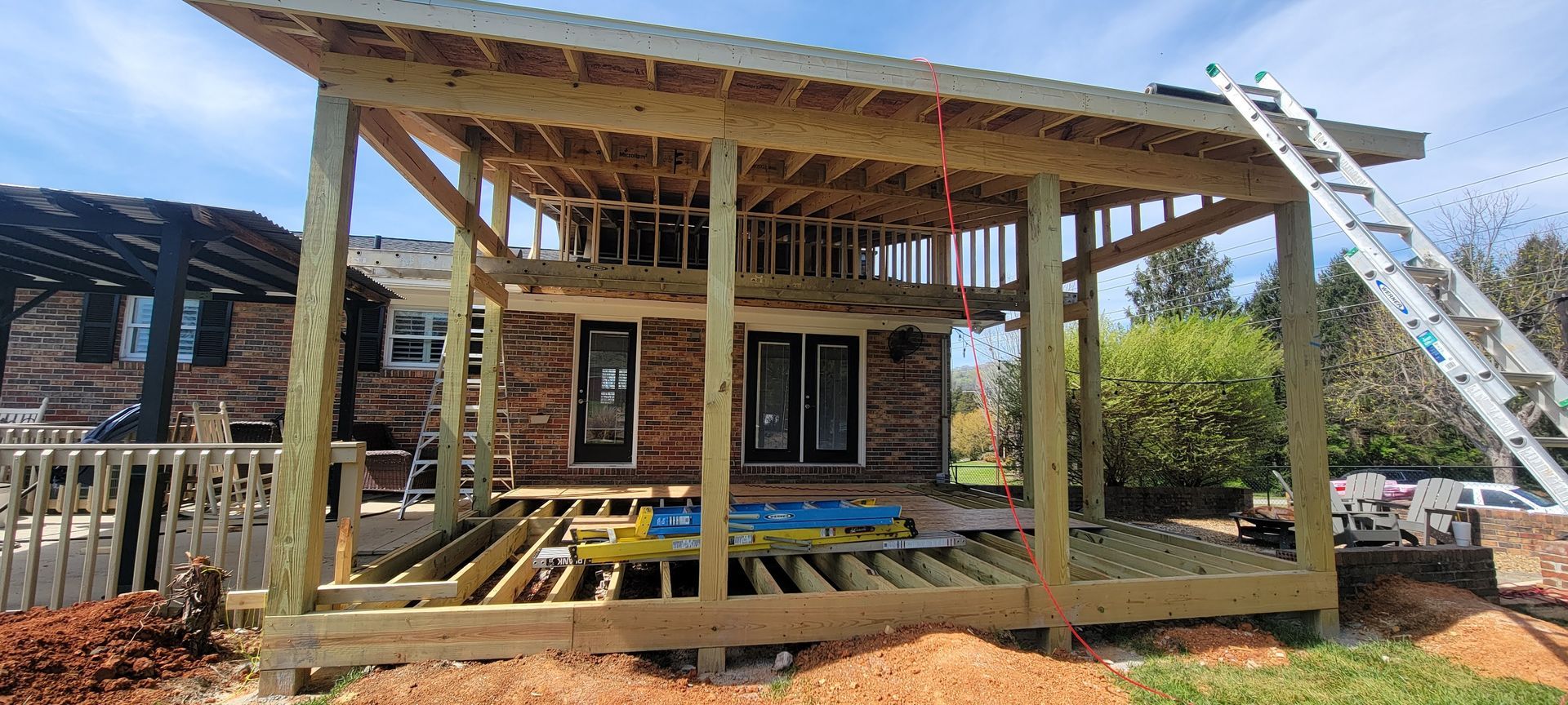 A wooden structure is being built in the backyard of a house.