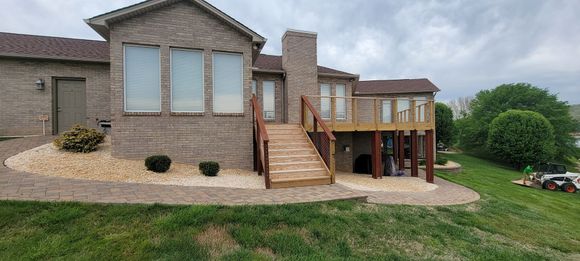 A large brick house with a wooden deck and stairs leading to it.