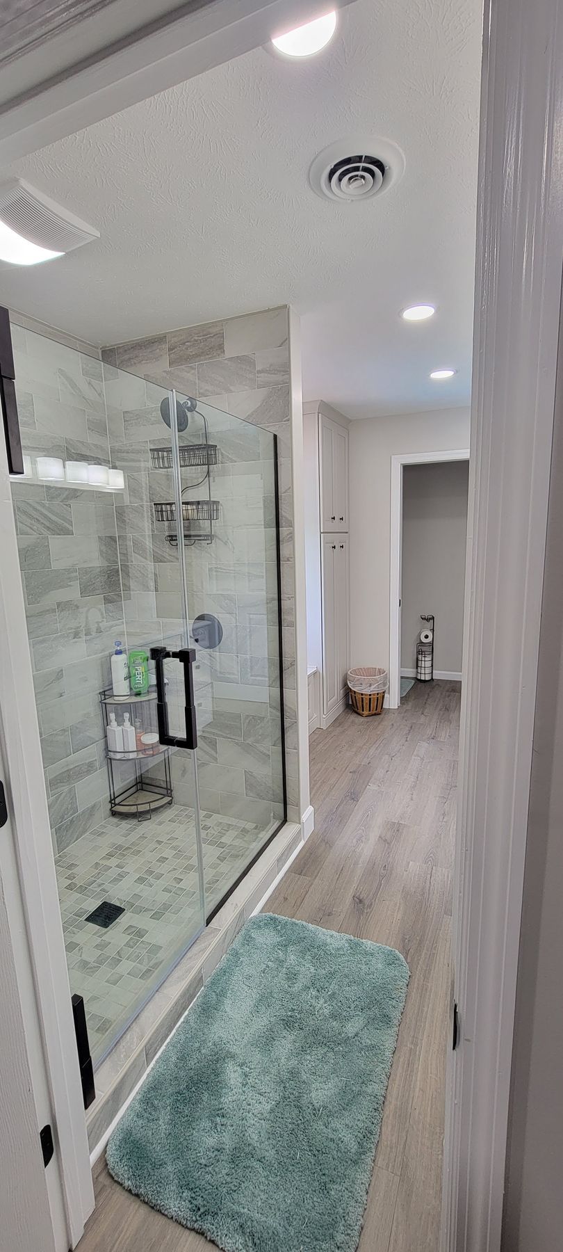 A bathroom with a walk in shower and a rug on the floor.