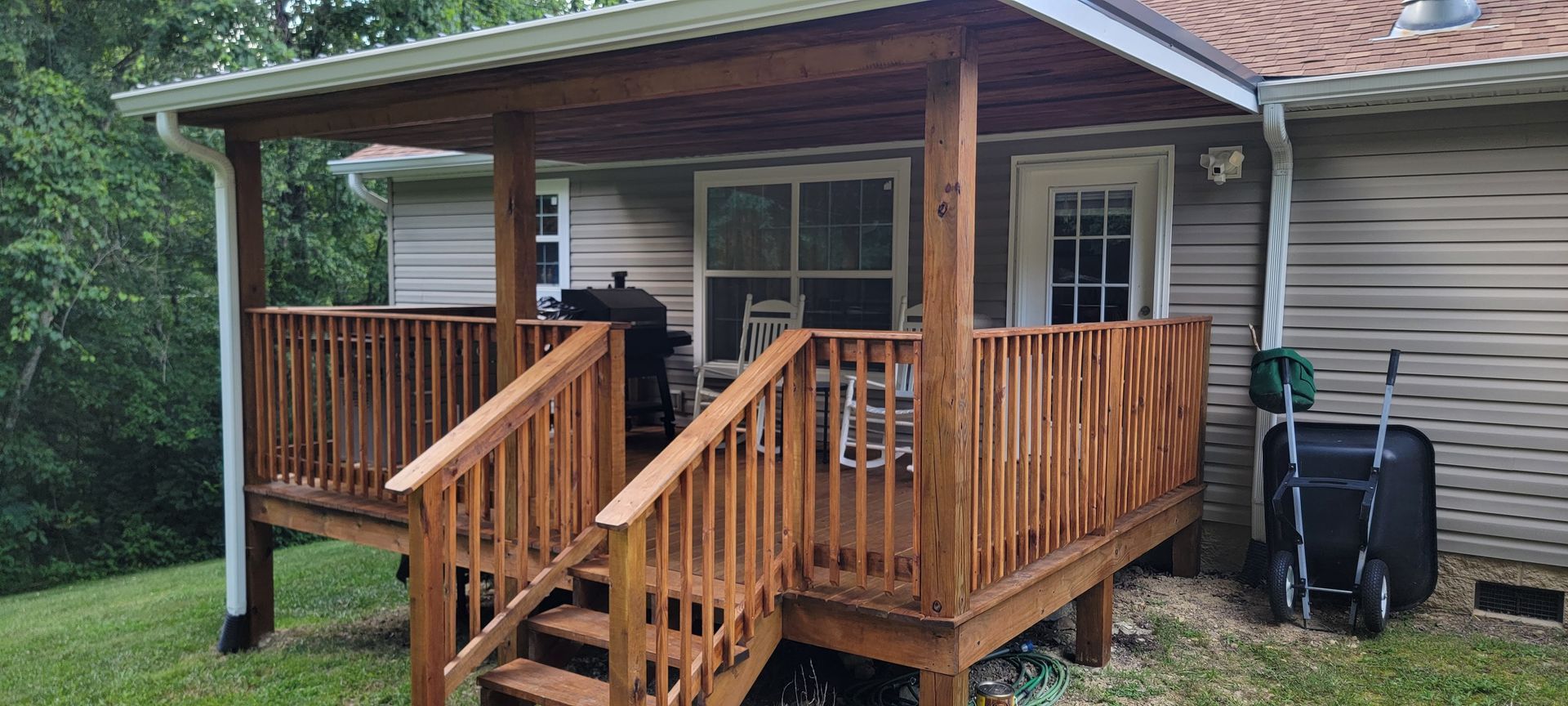 A wooden deck with stairs leading up to it is in front of a house.