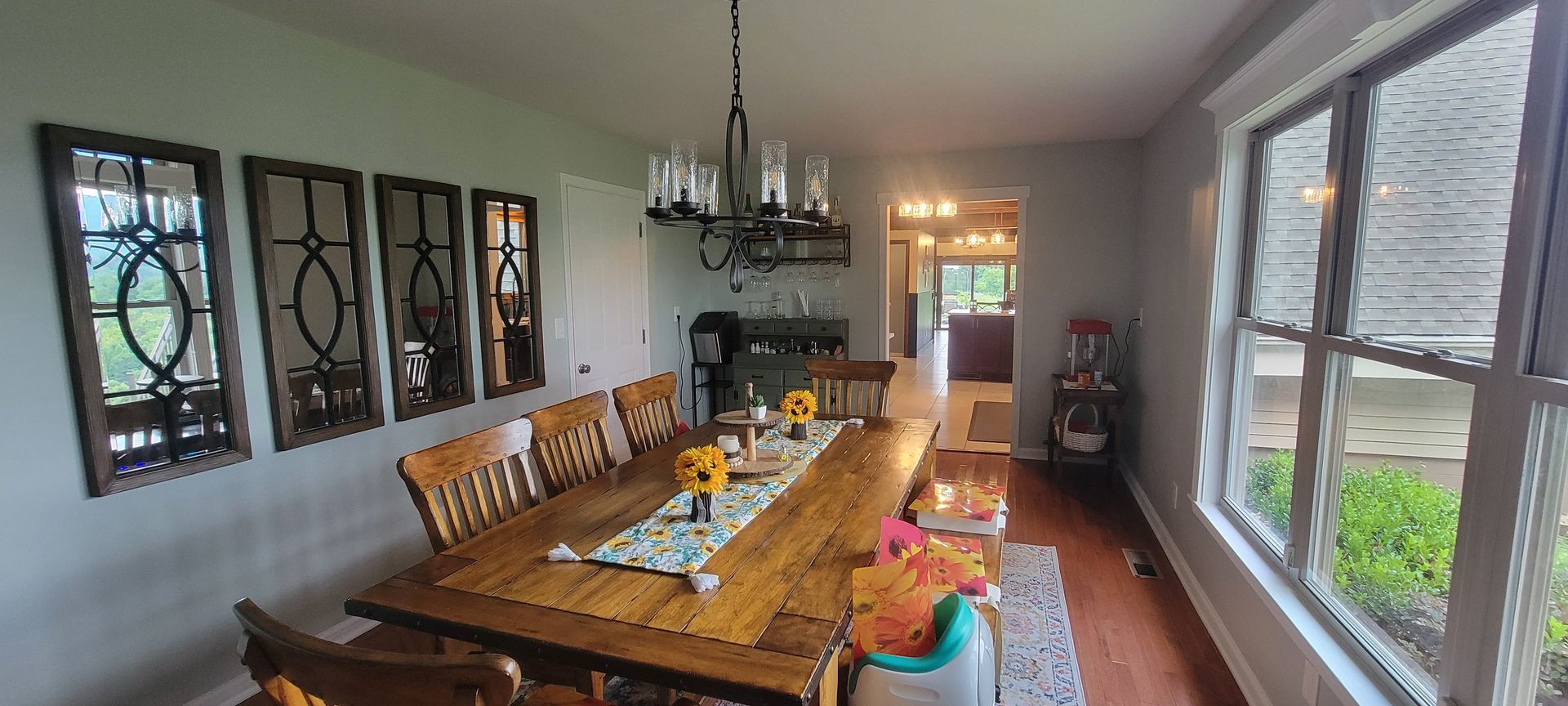 A dining room with a long wooden table and chairs and a chandelier.