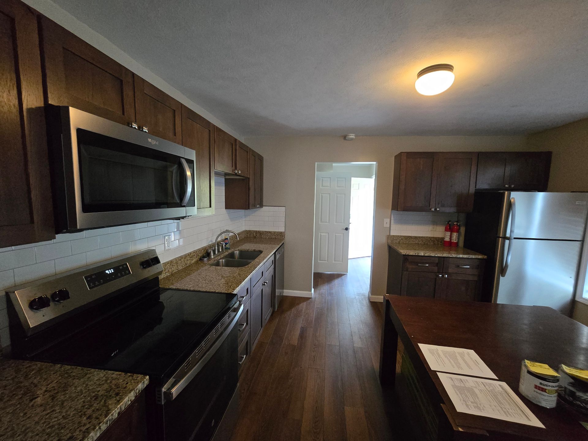A kitchen with a stove , microwave , refrigerator and sink.