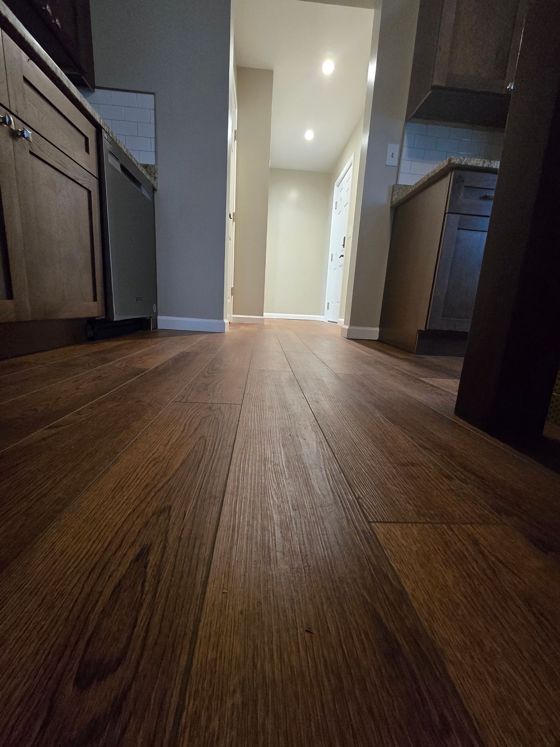 A kitchen with hardwood floors and cabinets and a hallway.