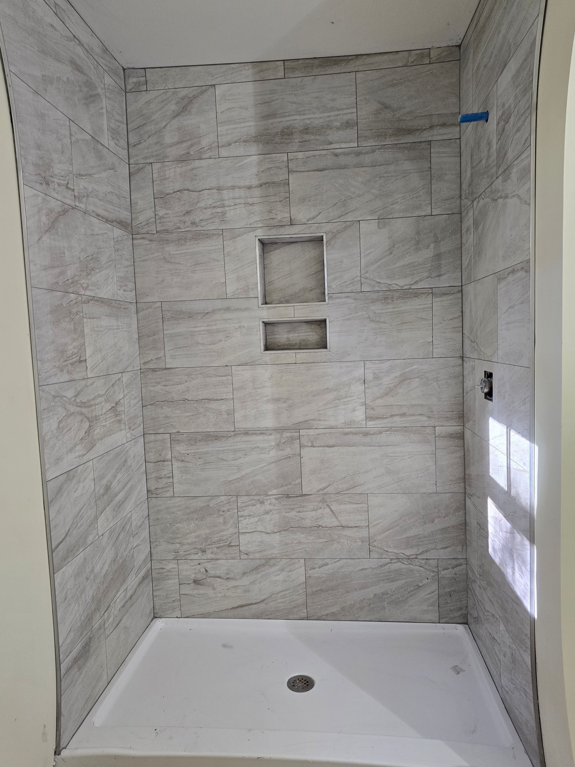 A bathroom with a walk in shower and a brick wall.