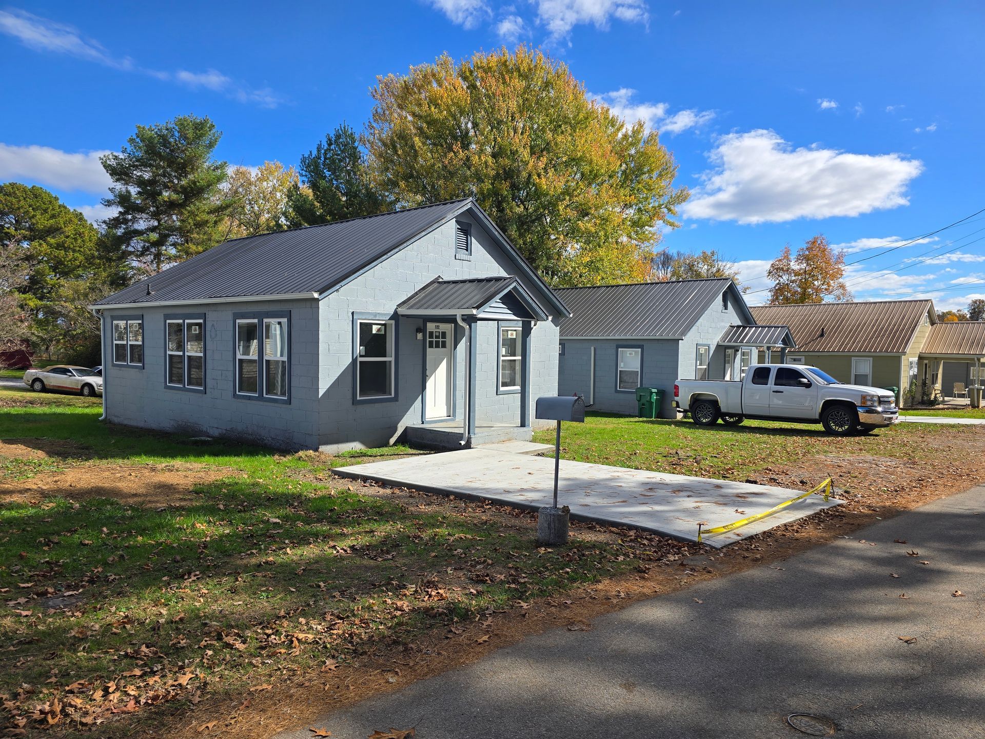 A white truck is parked in front of a small house.