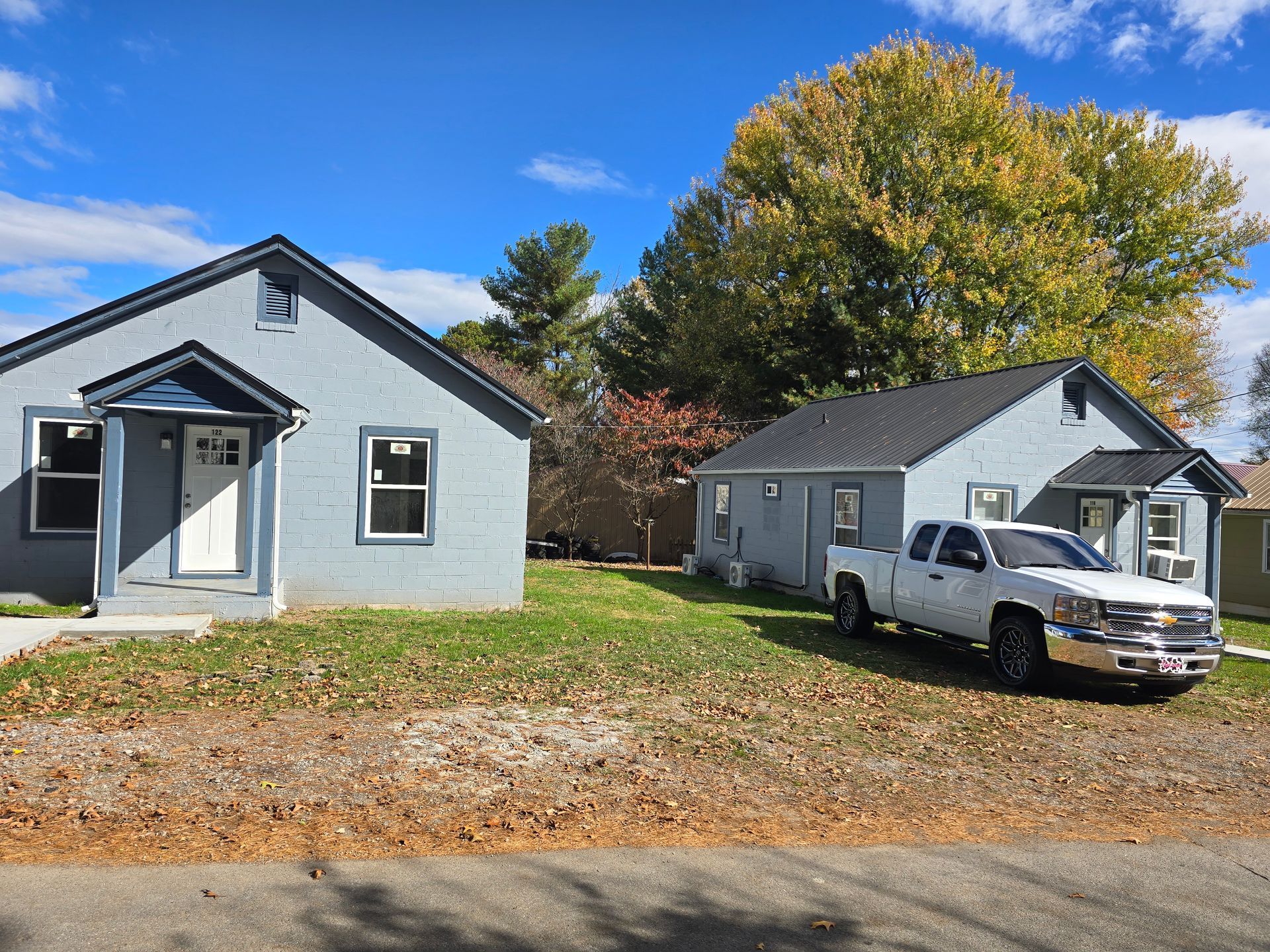 A white truck is parked in front of two houses.