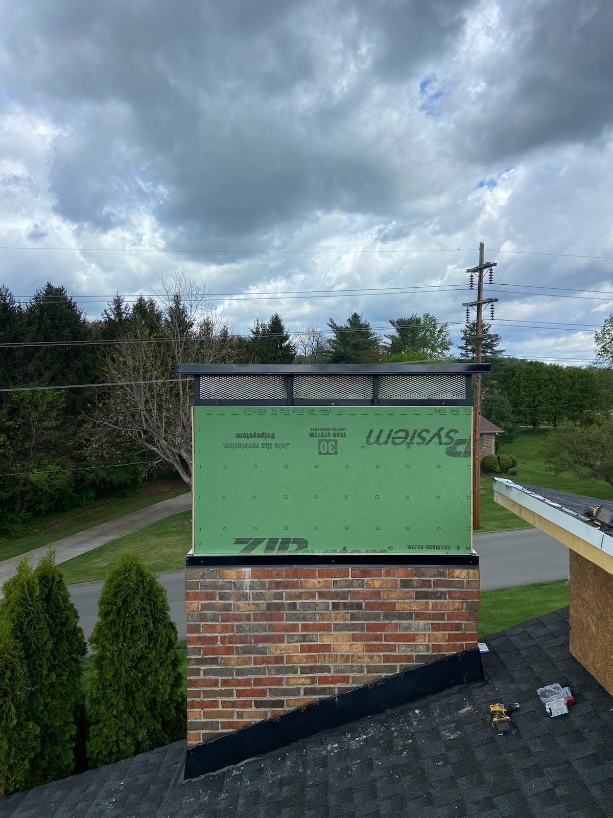 A brick chimney is being installed on top of a roof.
