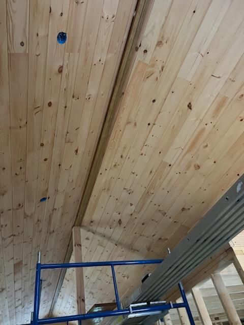 A blue scaffolding is sitting under a wooden ceiling