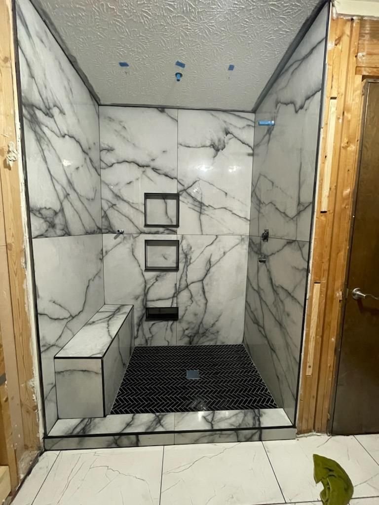 A bathroom with marble tiles and a walk in shower.