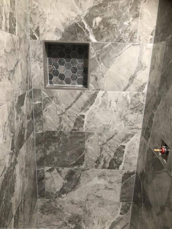 A shower with marble tiles and a niche in the wall.