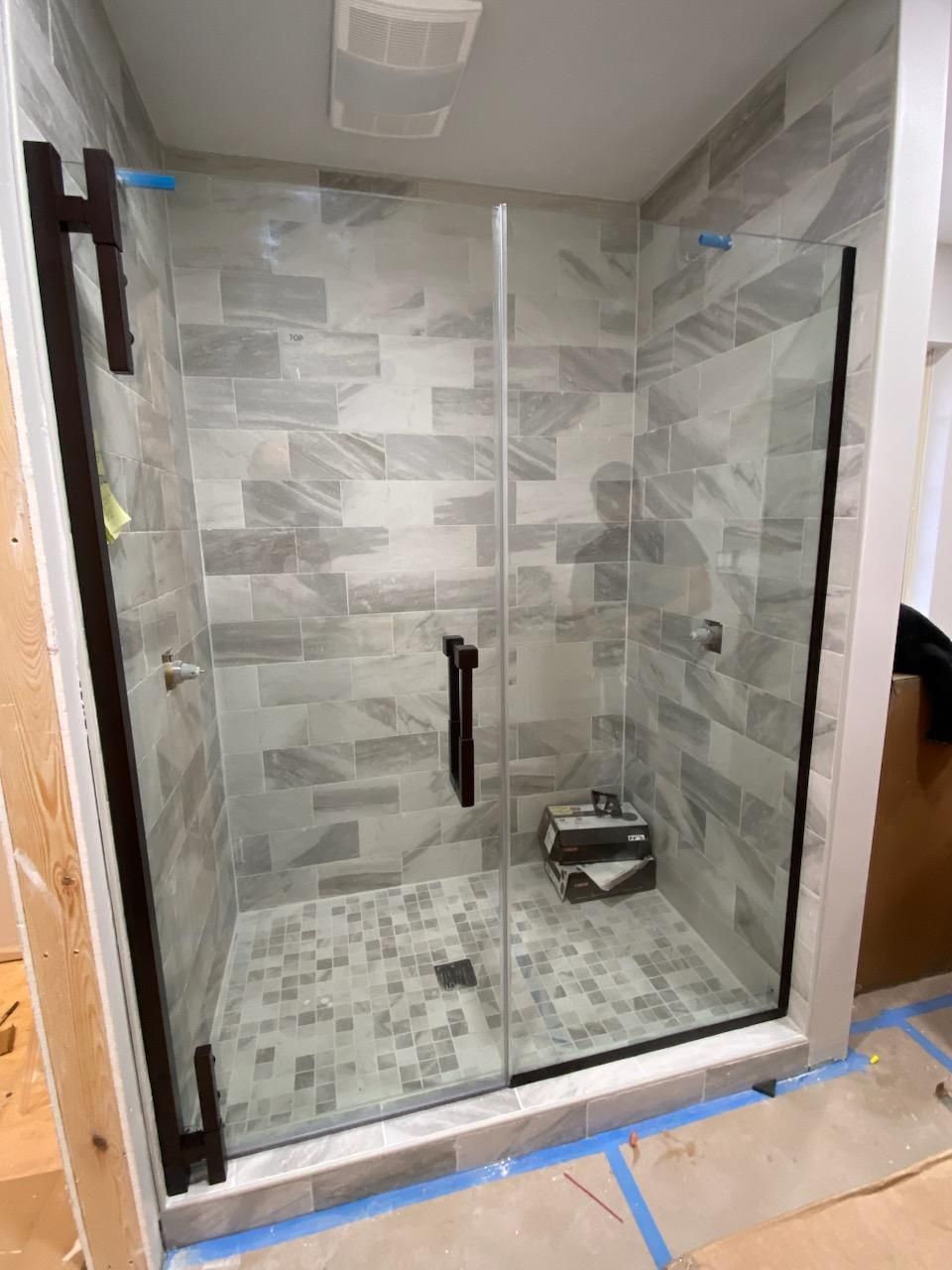 A shower stall with a glass door is being built in a bathroom.