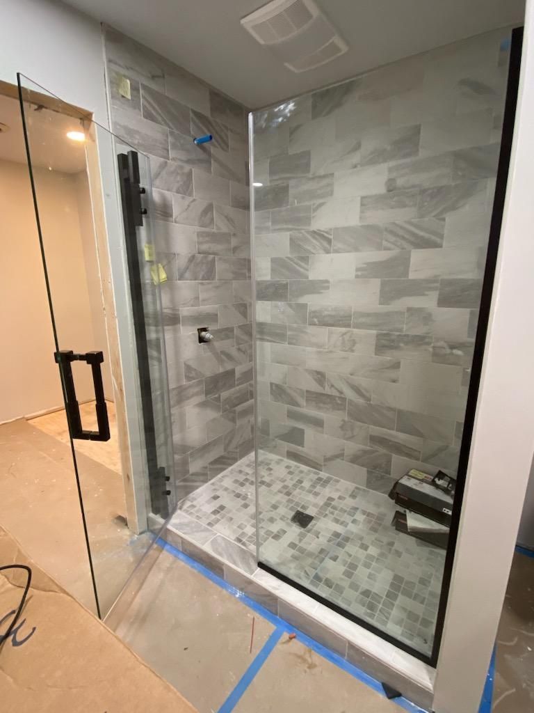 A bathroom with a walk in shower with a glass door.