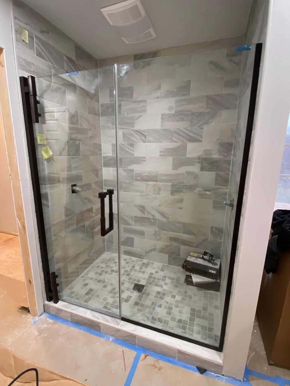 A shower stall with a glass door is being built in a bathroom.