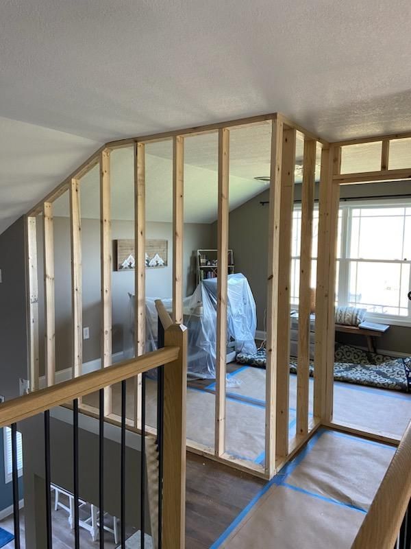 A room with a staircase and a wooden railing is being remodeled.