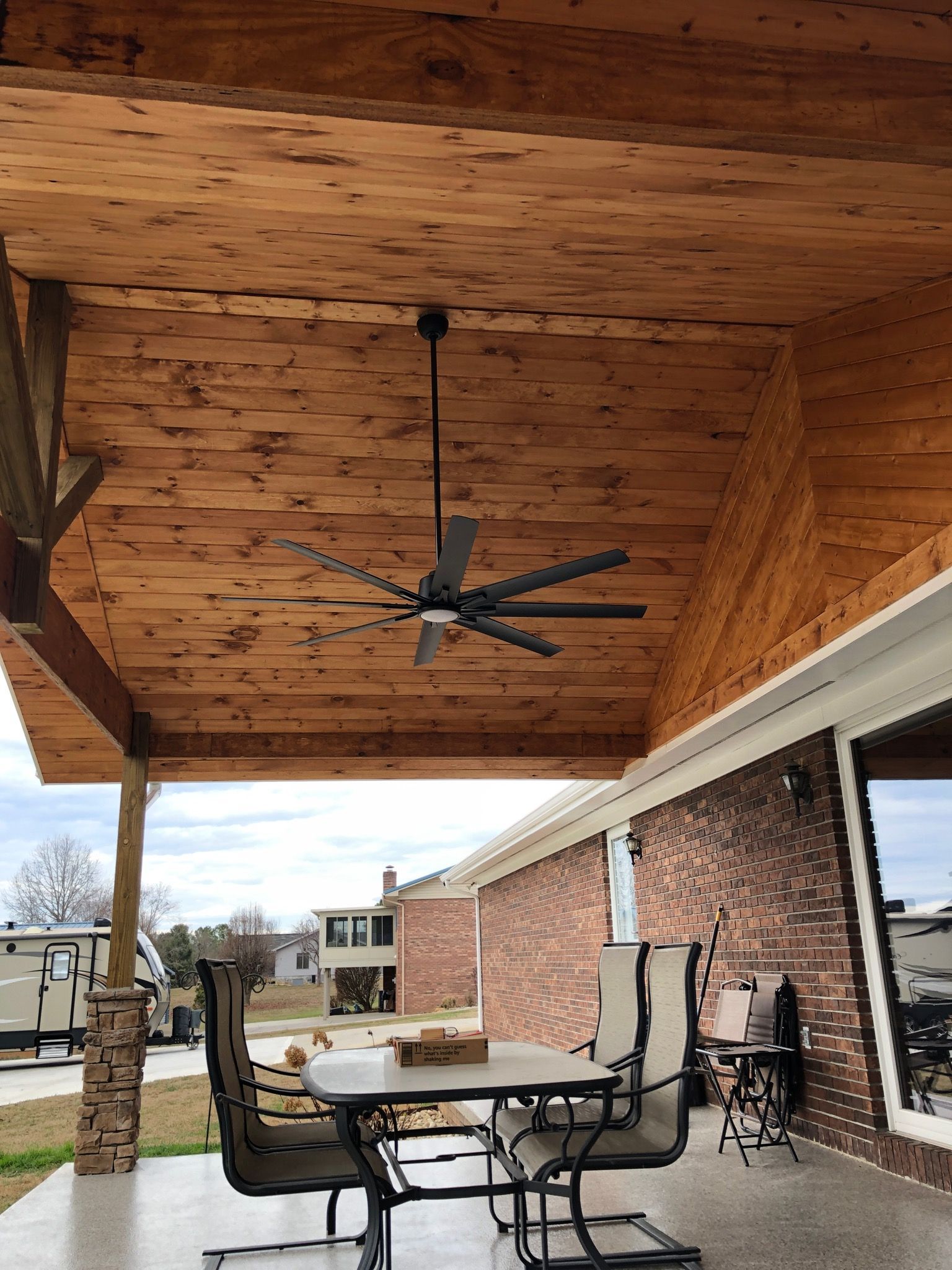 A wooden patio with a table and chairs and a ceiling fan.