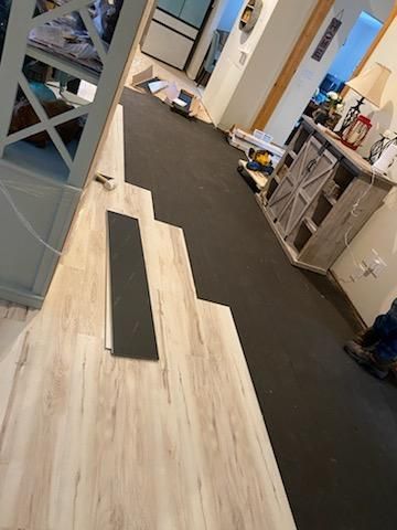 A wooden floor is being installed in a living room.