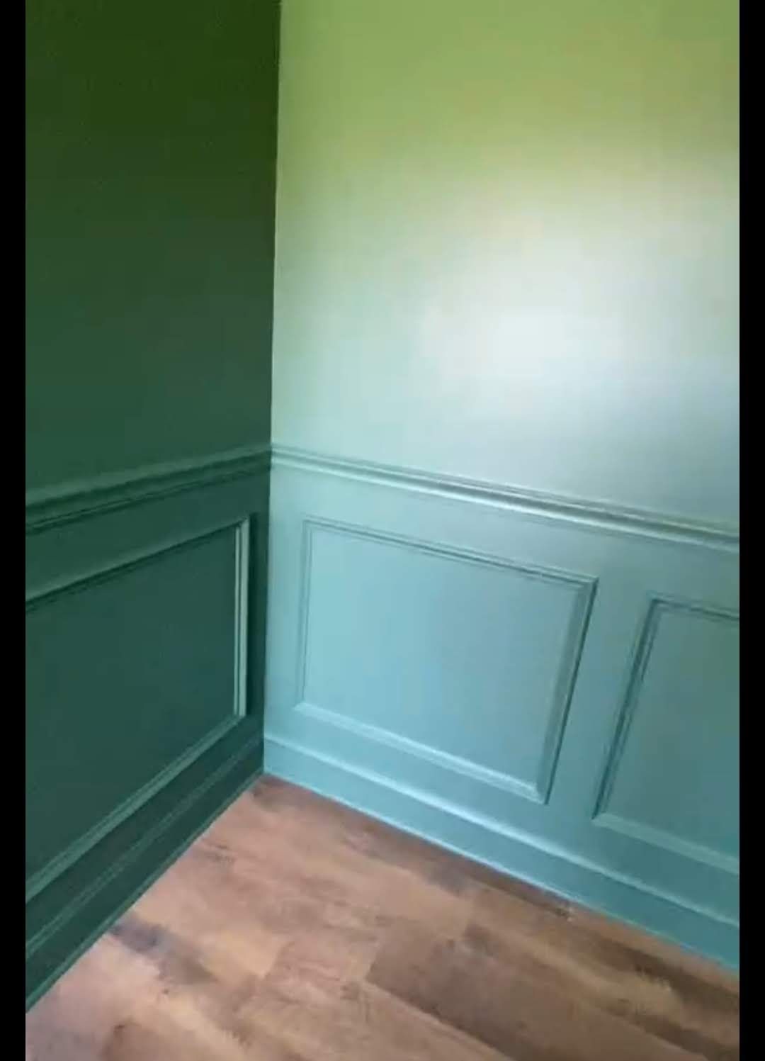 A room with green walls and a wooden floor.