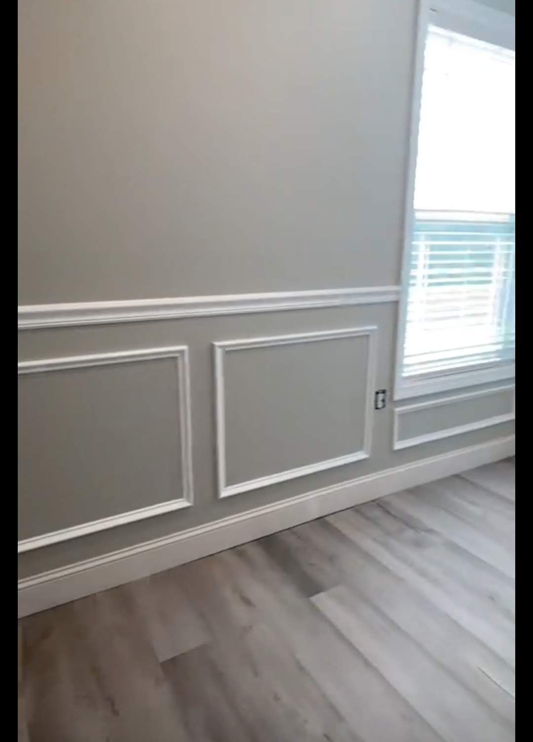 A room with gray walls and white trim and a window.