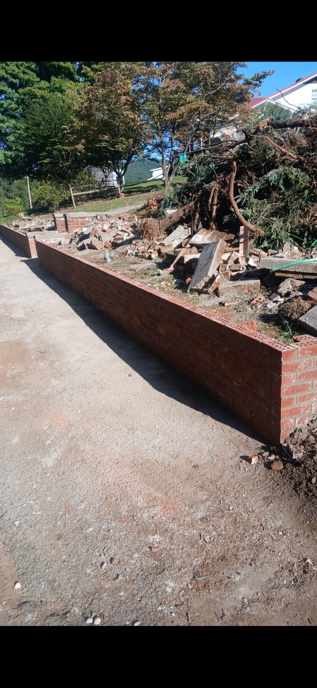 A brick wall is being built next to a gravel road.