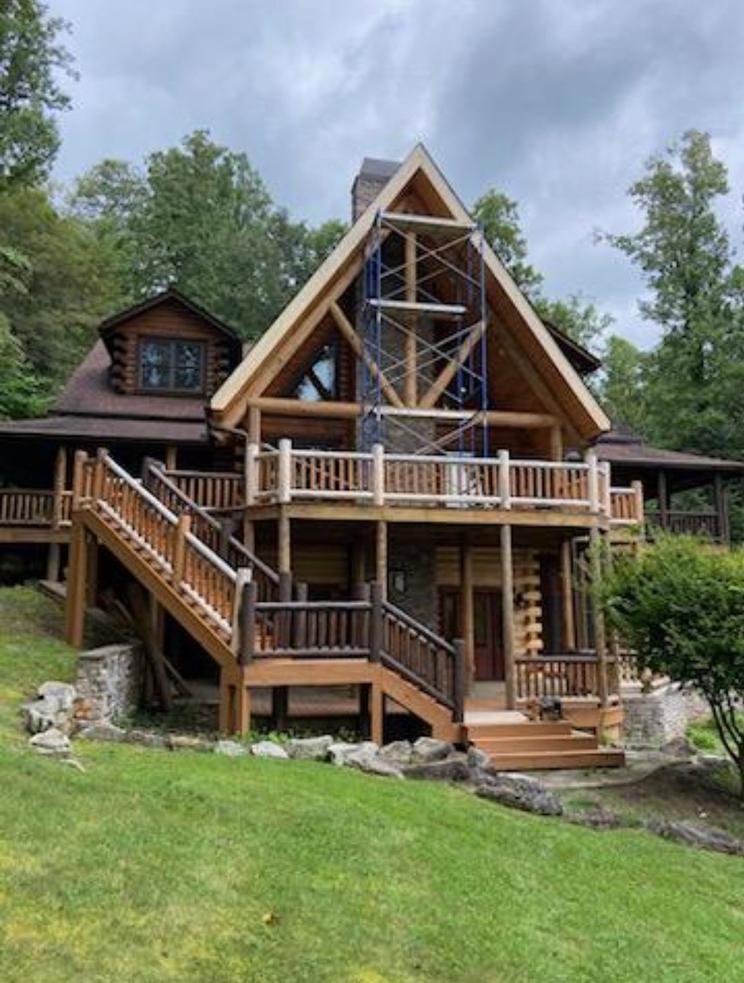 A large log cabin with a large deck and stairs