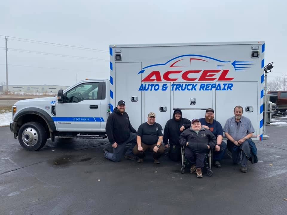 A group of men are posing for a picture in front of an ambulance.