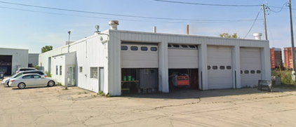 A white building with a lot of garage doors and cars parked in front of it.