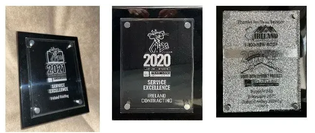 Three plaques with engraved text and logos against black frames.