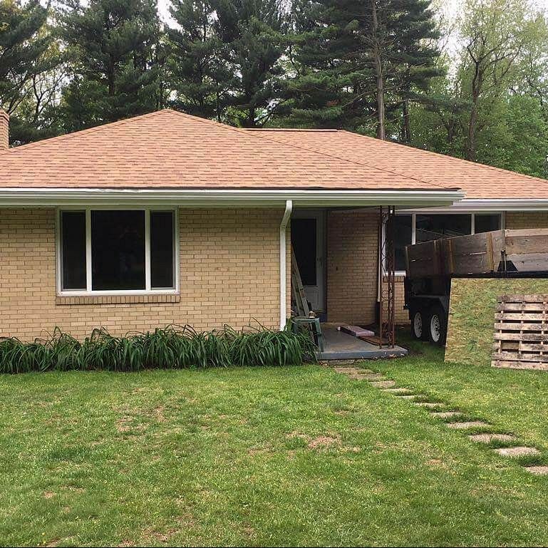 Tan brick house with brown roof and green lawn.