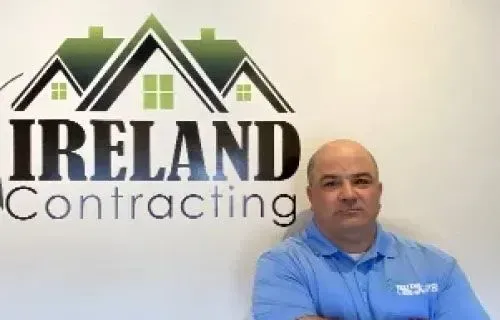 Man in blue polo shirt stands in front of 