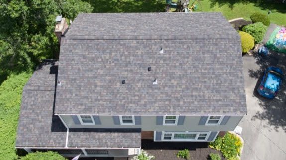 Overhead view of a two-story house with gray shingle roof, green siding, and blue shutters.