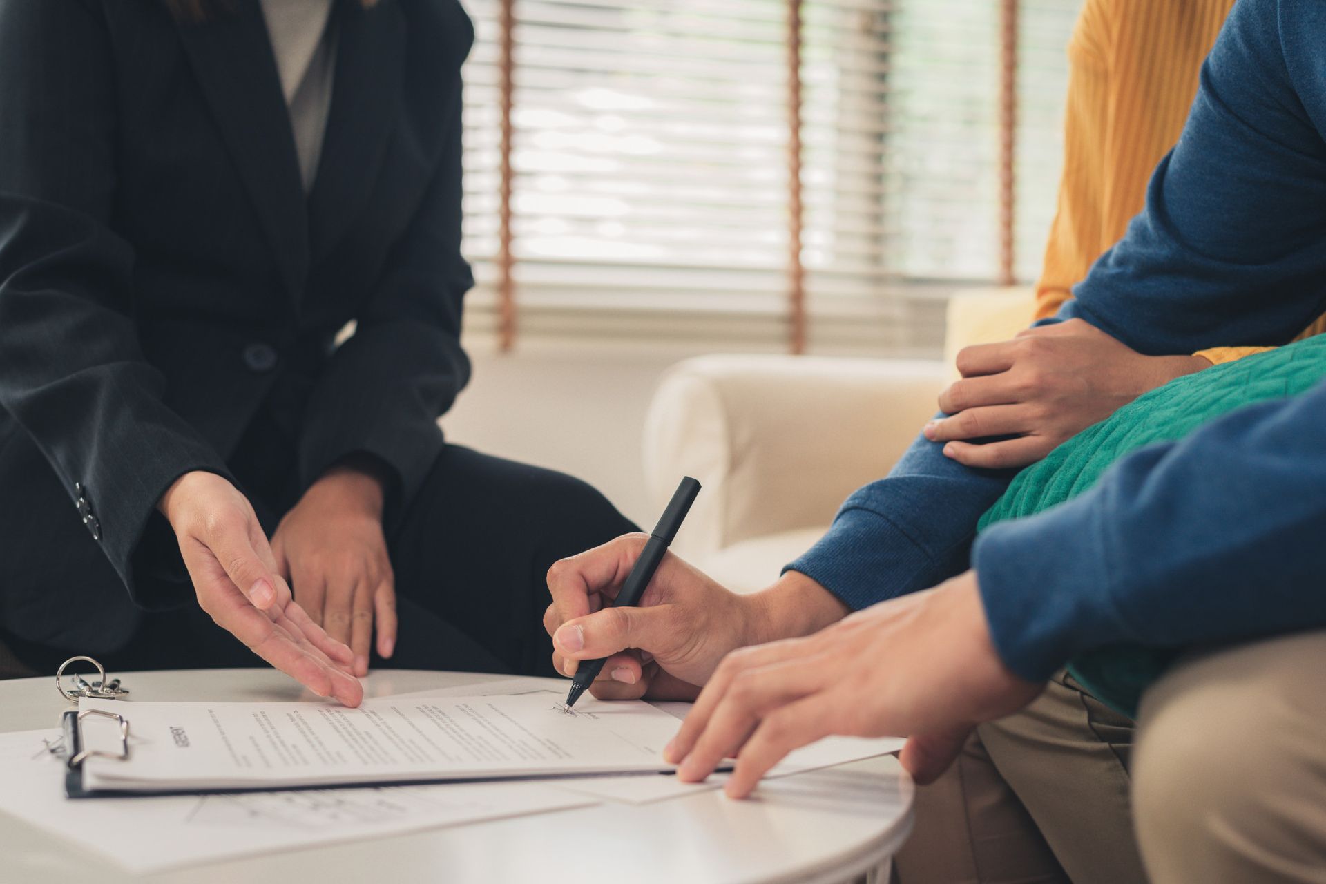 People signing paperwork during a consultation at a small table