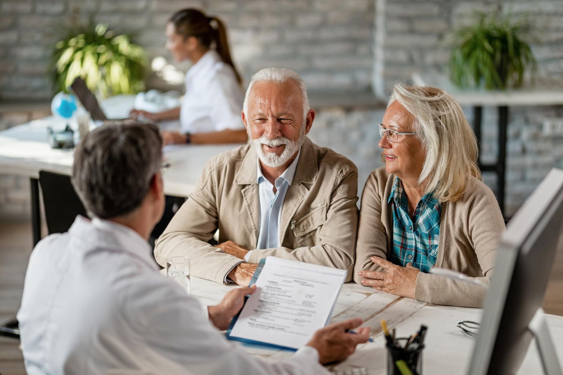 Business meeting with two clients reviewing documents across a desk in a bright office