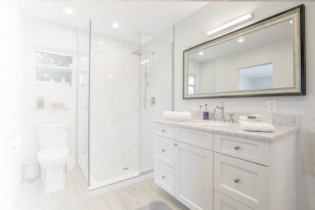 A bathroom with a walk in shower , sink , mirror and toilet.