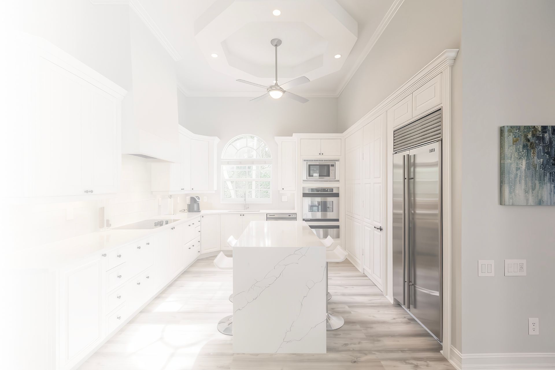 A kitchen with white cabinets , stainless steel appliances , and a large island.