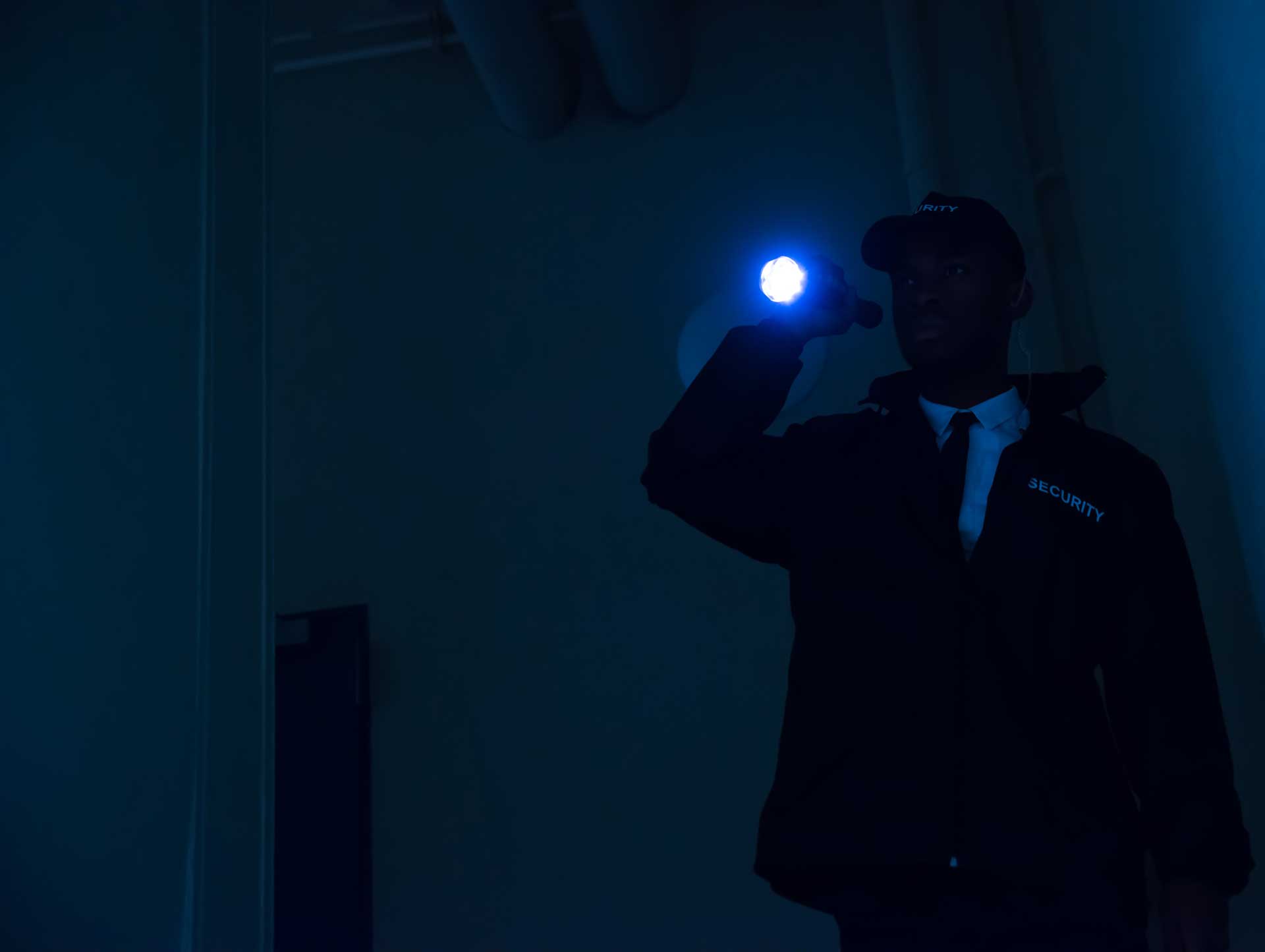 A security guard patrolling in the dark with a flashlight