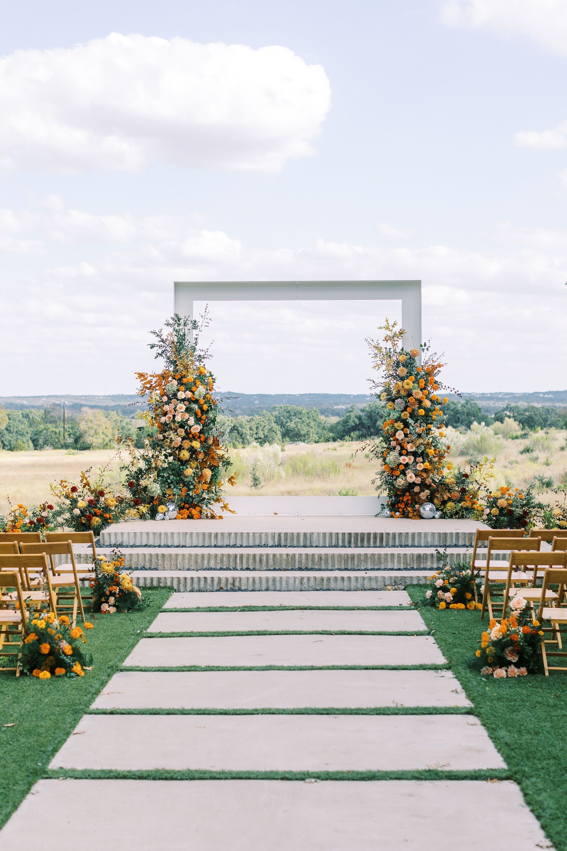 Outdoor wedding ceremony with floral arch, stone steps, and a view of nature.