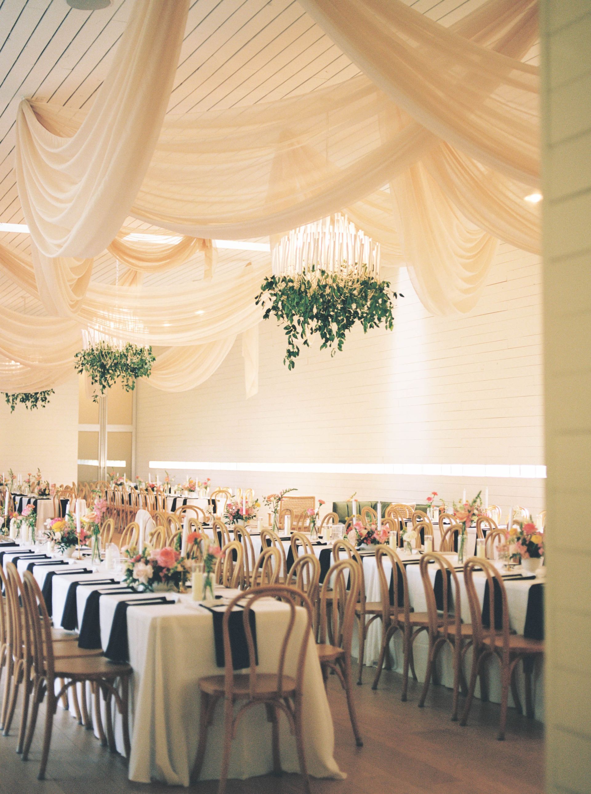 Elegant wedding reception with draped fabric ceiling and decorated tables.