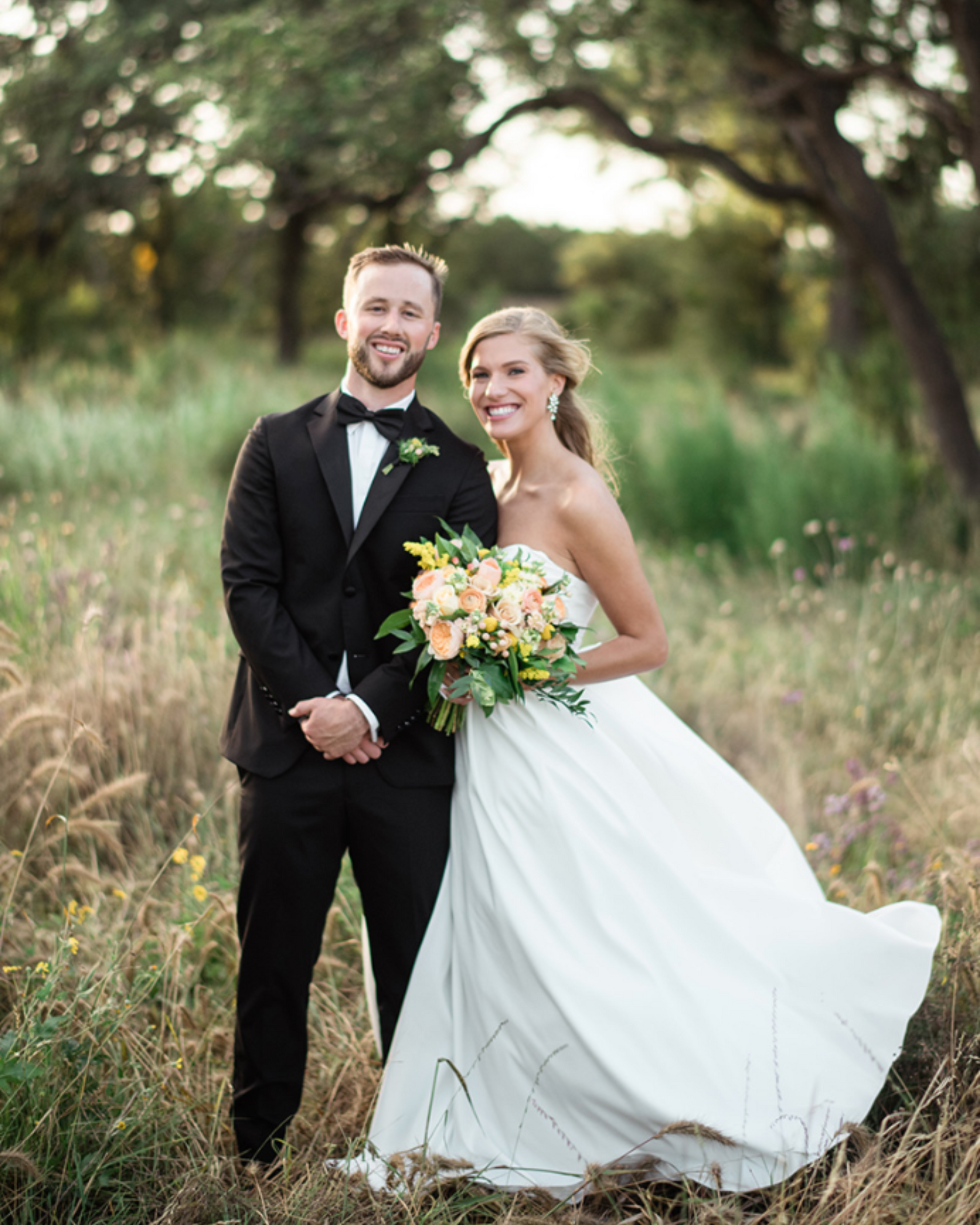 A bride and groom are posing for a picture in a field.