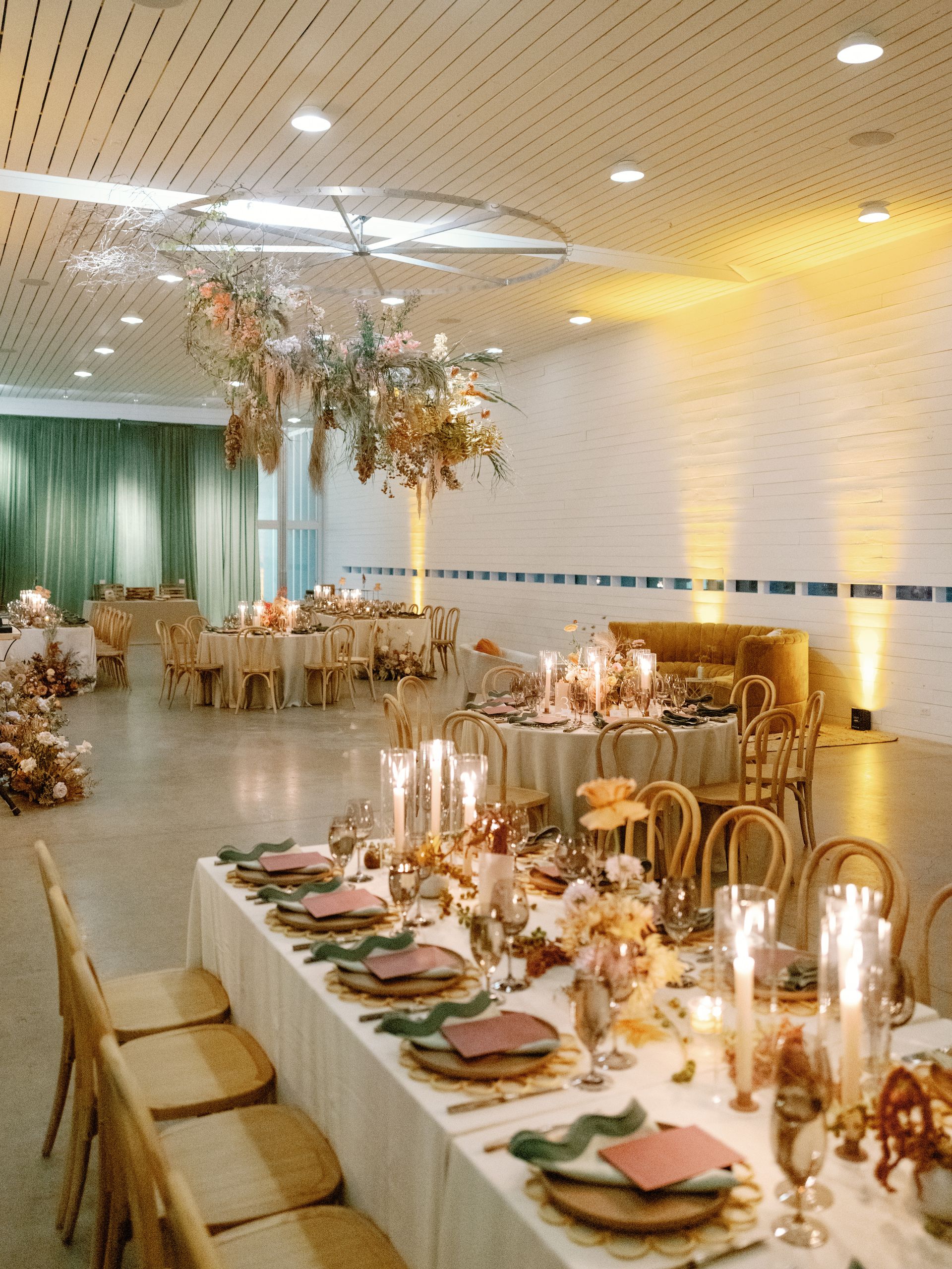 A long table with plates , candles , and chairs in a large room.