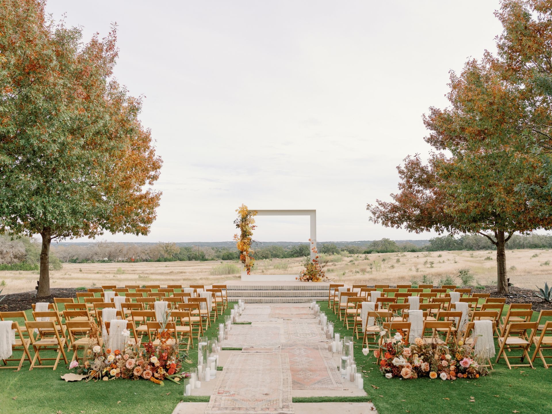 A wedding ceremony is taking place in the middle of a field surrounded by trees.