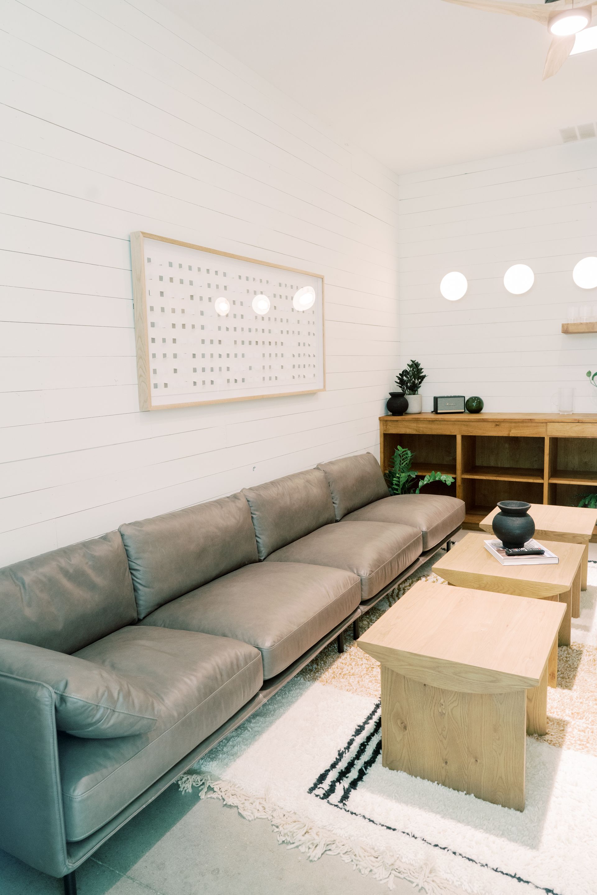 Gray sectional sofa, light wood coffee tables, and neutral rug in a modern, grooms suite at Prospect House.