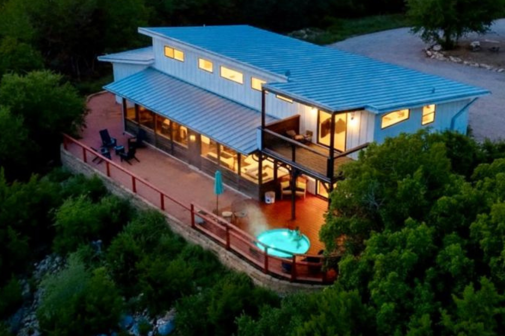 A group of cabin like houses with red chairs and a fire pit in front of them