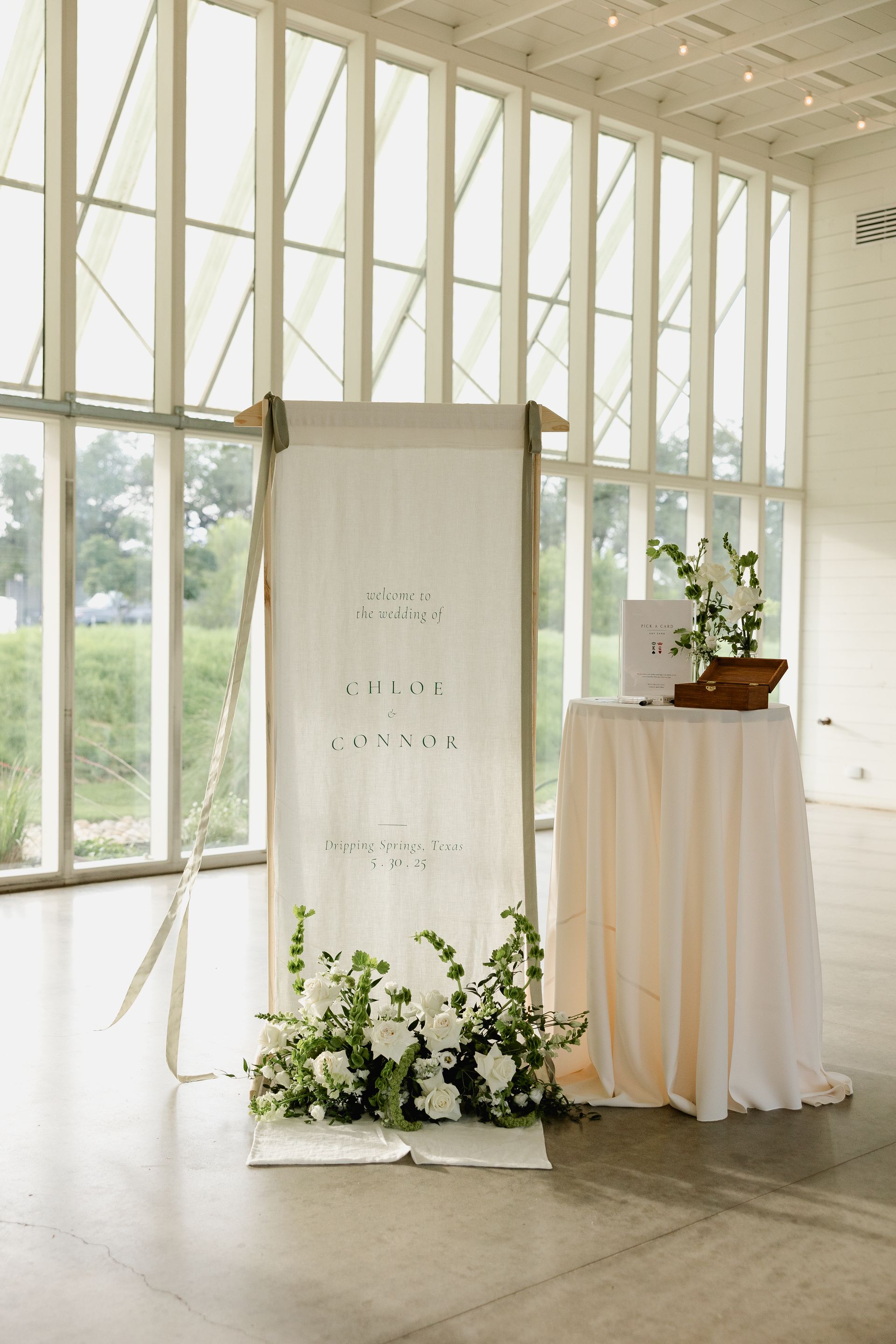 Wedding welcome sign and table in Prospect House's light-filled modern building, greenery, neutral colors.