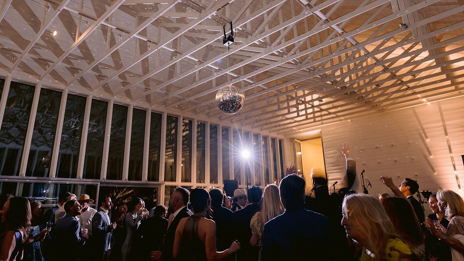 A group of people are dancing in a room with a disco ball hanging from the ceiling.