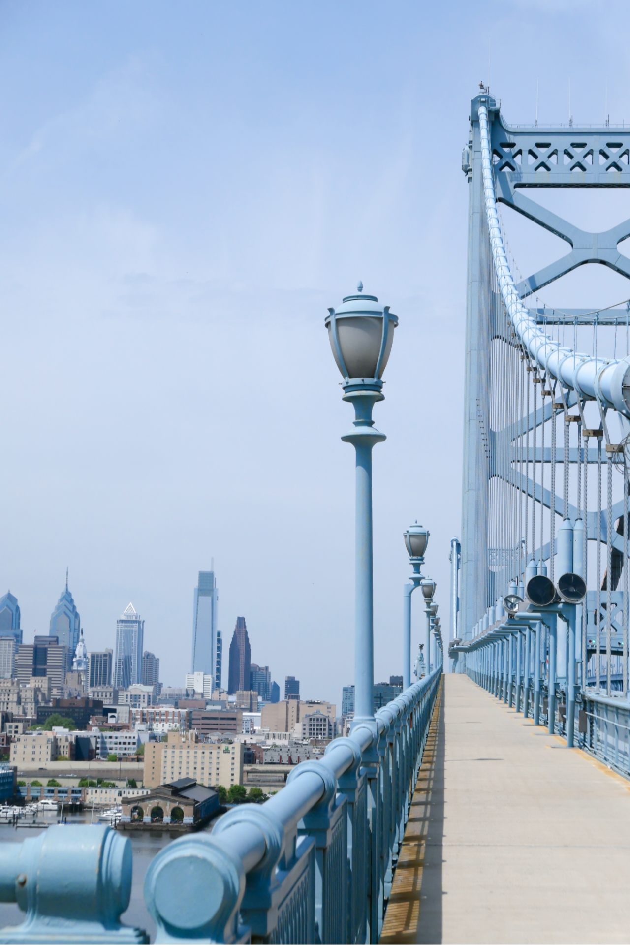 A red car is driving down a city street with tall buildings in the background.
