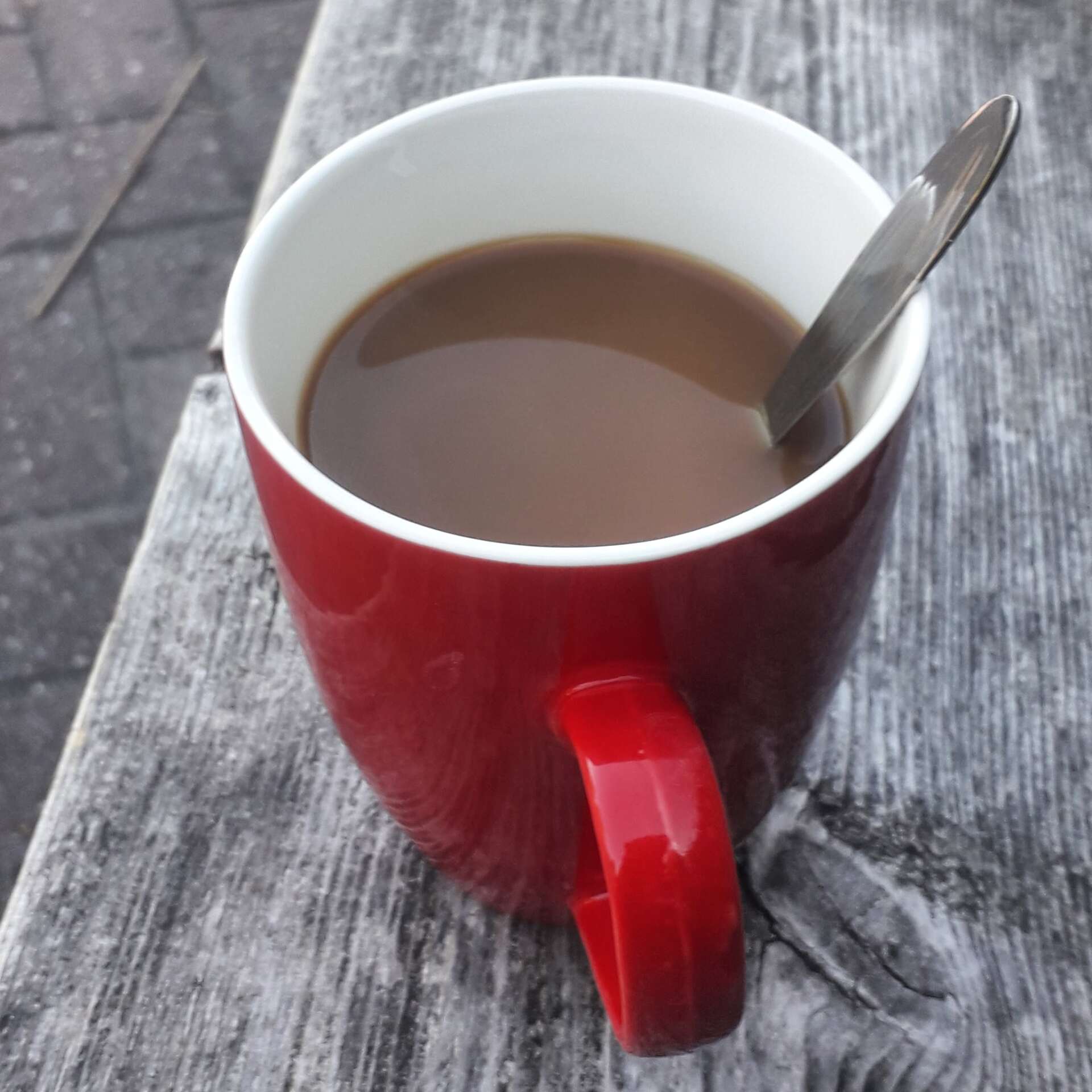 Een rode kop koffie met een lepel erin