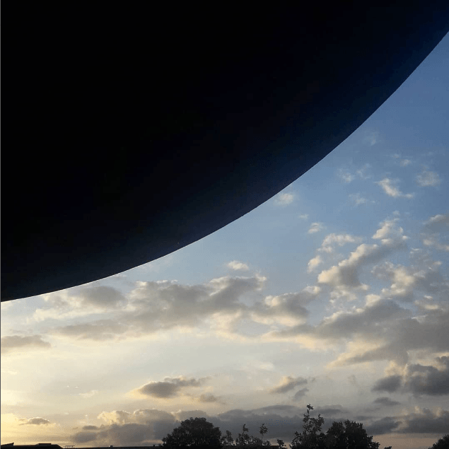 Een blauwe lucht met witte wolken en bomen op de voorgrond